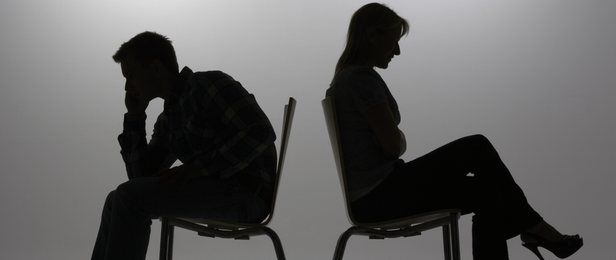 Les silhouettes d’un homme et d’une femme assis dos à dos et faisant face en direction opposée